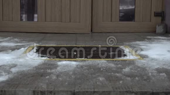 雪覆盖的楼梯和门廊上的特写男人打开一栋大楼的门走到外面的城市街道视频的预览图