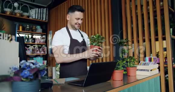 花店老板用笔记本电脑在笔记本上写绿色植物视频的预览图