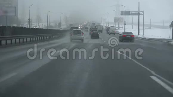 降雪时在高速公路上乘车从驾驶室内通过挡风玻璃观看冬天的白天恶劣天气视频的预览图