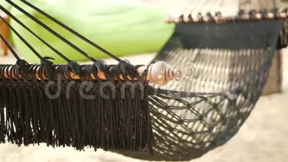黑色吊床伸展在椰子手掌之间网眼老式的hipster吊床边缘延伸在沙地上视频的预览图