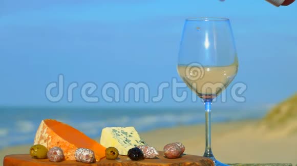 红酒倒入靠近奶酪和橄榄的玻璃杯中视频的预览图