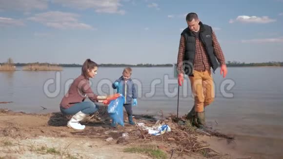 爱护自然生态家庭志愿者带着小儿子在肮脏的水边清理塑料和聚乙烯垃圾视频的预览图