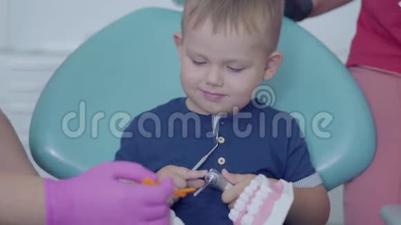可爱的小男孩在牙医办公室玩下巴模拟托管儿童出诊医生牙科治疗视频的预览图