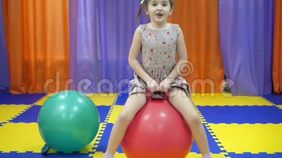 孩子们游戏室小女孩跳在体操球上视频的预览图