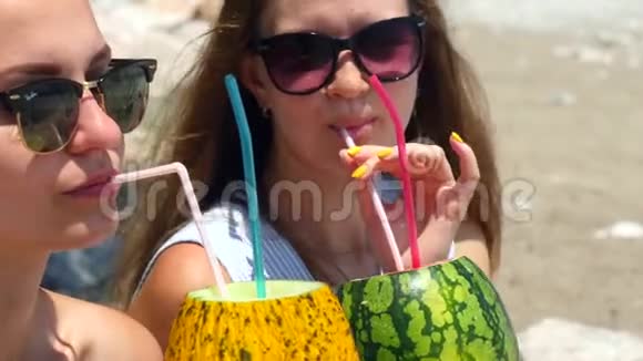 年轻漂亮的女孩戴着墨镜喝着新鲜的水果鸡尾酒视频的预览图