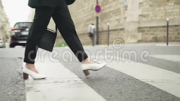 在斑马线上行走时穿着白色靴子的女人的腿缓慢移动视频的预览图