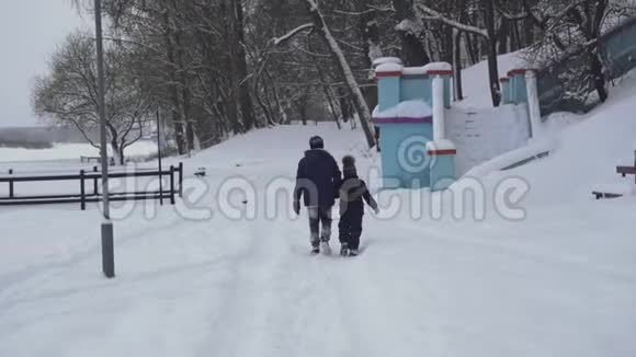 哥哥和弟弟或朋友在冬天牵着手在雪地里散步童年时的友谊视频的预览图