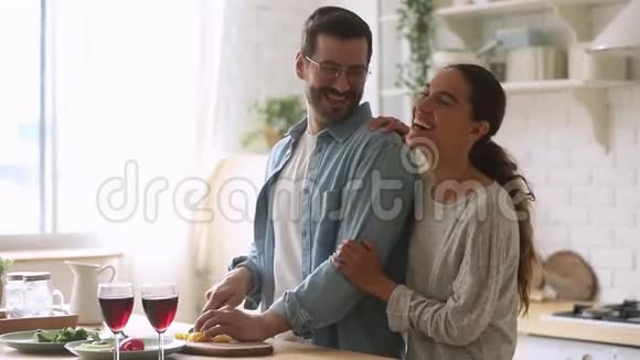 快乐的年轻夫妇一起做饭一起准备厨房里健康的饭菜视频的预览图