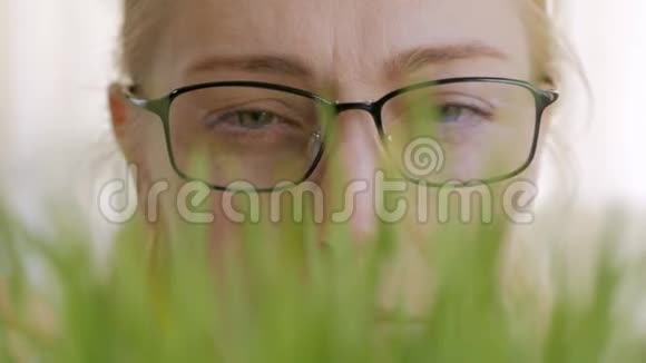 一个女人戴着眼镜脸的特写考虑到绿色植物的生长茎视频的预览图
