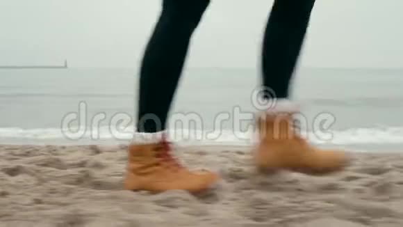 黄靴女足在雾中漫步海滩寒冷的秋日视频的预览图