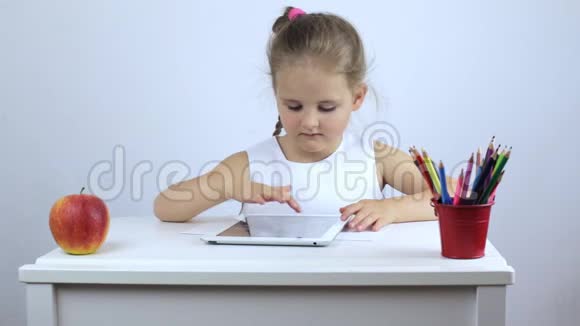 小女孩正坐在书桌前正在买一块平板电脑视频的预览图