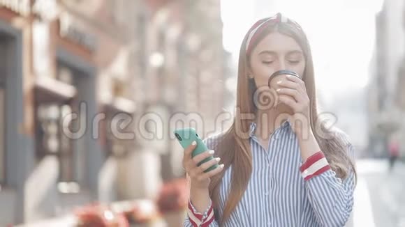 漂亮时尚的白种人年轻女孩的肖像她的棕色头发上有头巾用她的智能手机和微笑视频的预览图