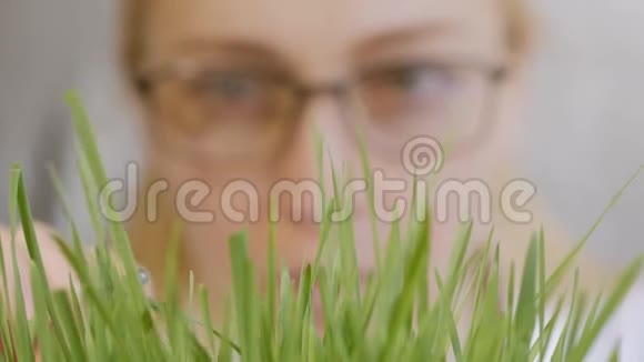 一个女人戴着眼镜脸的特写考虑到绿色植物的生长茎视频的预览图