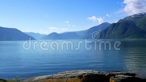 美丽的画面宁静的峡湾和高山景观与蓝色的水和天空鸟类在岩石海岸的前景视频的预览图