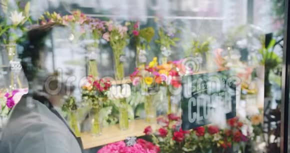穿围裙的男花匠在花店门上微笑着换了个封闭的标志视频的预览图
