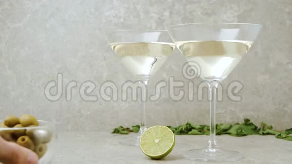 豪华马提尼手把一个装有橄榄的碗放在桌子上上面装饰着鸡尾酒棒石灰薄荷和带马提尼的玻璃杯视频的预览图