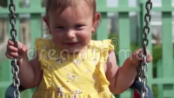 快乐的宝宝在操场上的夏日摇摆慢动作视频的预览图