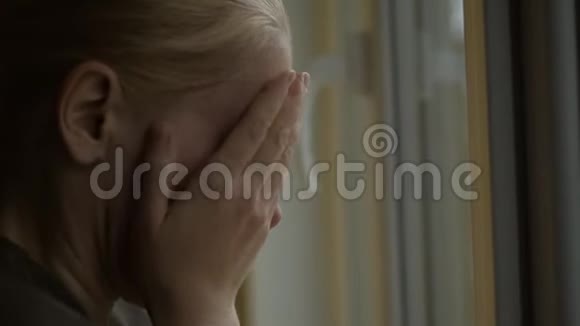 女人站在房间的窗户边哭着用手捂住脸外面雨滴在地上视频的预览图