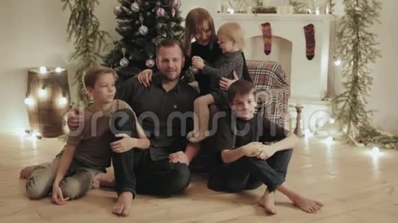 一个五口之家父亲母亲两个儿子和一个女儿在圣诞节期间在家里的一个房间里聊天视频的预览图