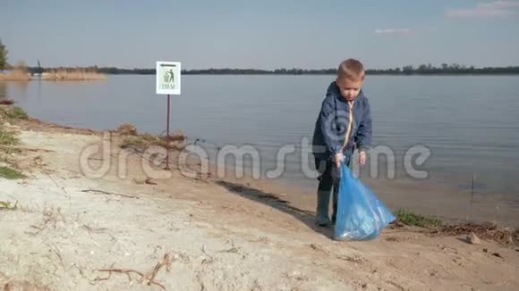 儿童对垃圾儿童男孩在清理塑料后在河堤上的标志上拉着沉重的垃圾袋视频的预览图