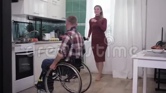 幸福的家庭坐轮椅的男人正在厨房和妻子跳舞做饭视频的预览图