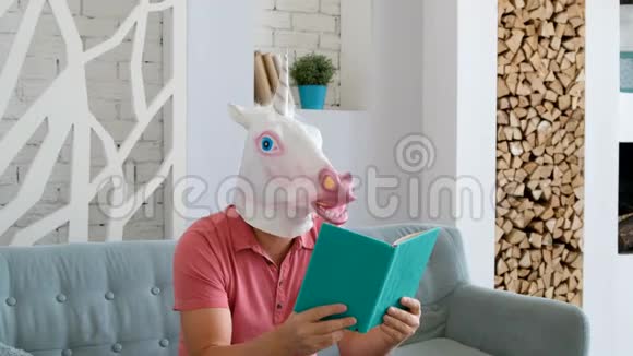 奇怪的搞笑视频戴着独角兽面具的男人坐在沙发上看书视频的预览图