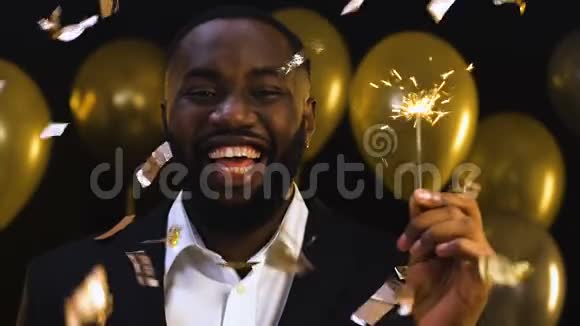 微笑的黑人男子与孟加拉灯站在下降的纸屑下庆祝视频的预览图