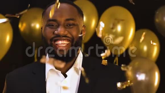 微笑黑人男子站在坠落的纸屑派对装饰视频的预览图