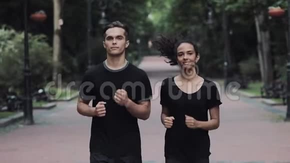 年轻的白种人男子和穿着慢跑服的穆斯林女孩在公园里轻松愉快地跑步视频的预览图