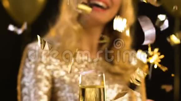 微笑的金发女郎拿着一杯香槟和孟加拉灯纸屑掉落视频的预览图