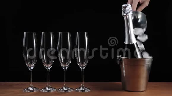 好香槟酒四个空杯子香槟酒立在木桌上背景黑色冰倒进桶里视频的预览图