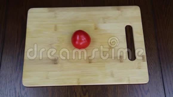 用手在木制砧板上切割红色成熟番茄食物视频的预览图