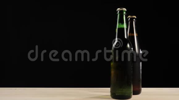新鲜啤酒在木桌上放着美味的手工啤酒放在绿色和棕色瓶子附近视频的预览图