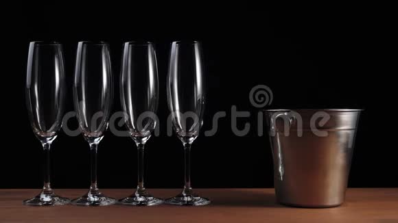 好香槟酒四个带香槟的空杯架在黑色背景的木桌上冰倒进桶里视频的预览图