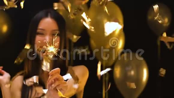快乐的亚洲小姐手里拿着银灯在飘落的纸屑下派对装饰视频的预览图