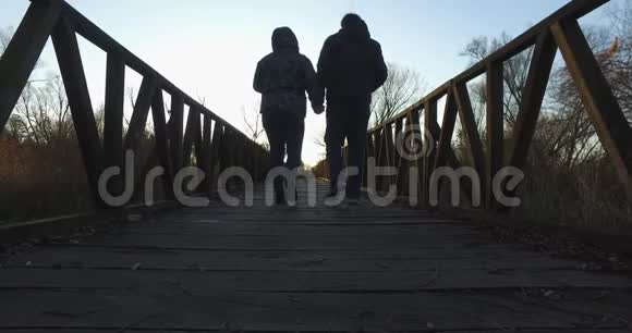 秋天在湿地环绕的自然公园里散步的女孩和男孩这条小路是由一条背景为b的木制长廊构成的视频的预览图