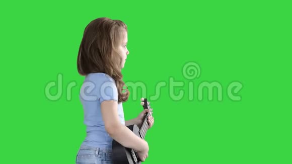 一个小女孩手里拿着四弦琴走在绿色的屏幕上铬钥匙视频的预览图