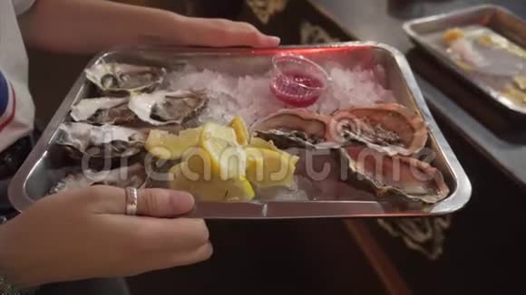 新鲜的牡蛎放在一个小女孩手里拿着冰酱汁和柠檬的托盘上视频的预览图