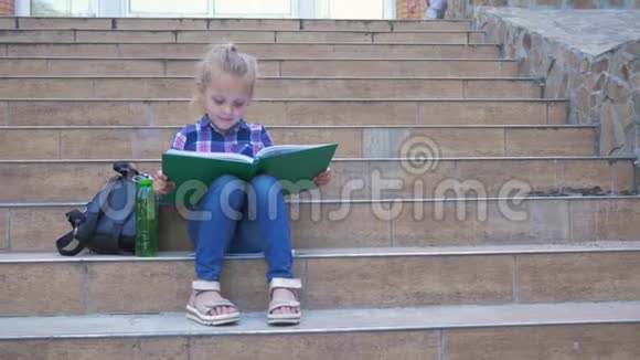 学校课间休息女学生背着背包坐在台阶上看书男同学跑到她旁边坐着视频的预览图