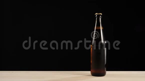 新鲜啤酒在黑色背景的木桌上用一瓶棕色的美味工艺啤酒递给我冰镇啤酒视频的预览图