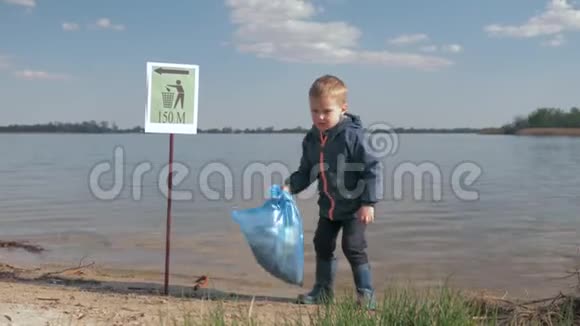 大自然中的生态污染垃圾问题清理塑料后手拿垃圾袋的小男孩画像视频的预览图
