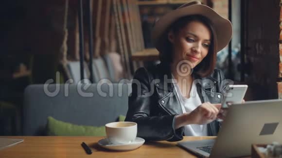 漂亮的年轻女性在咖啡馆里使用智能手机享受社交媒体的微笑视频的预览图