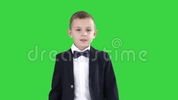 穿西装的友好小男孩打招呼然后在绿色屏幕上说再见色度键视频的预览图