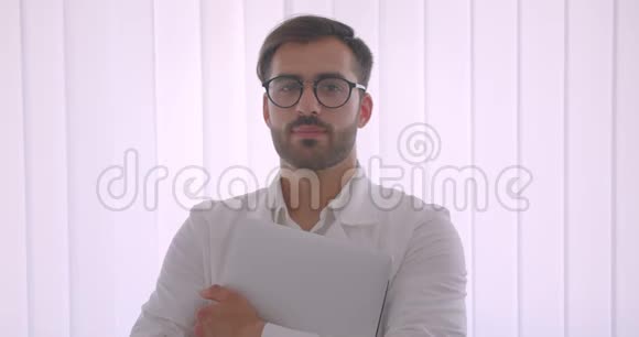 戴着笔记本电脑的英俊白种人商人戴着眼镜看着镜头笑得很开心视频的预览图