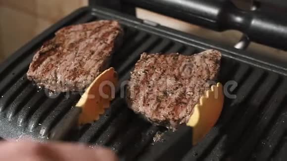 厨师从烤架上拿起成品多汁的牛肉肉做牛排视频的预览图