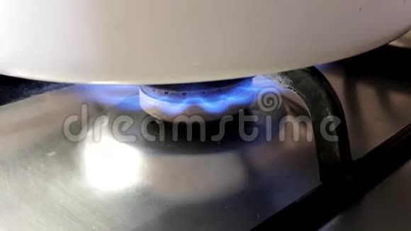 用燃烧的蓝色火焰在煤气炉上盖上一个白色的锅视频的预览图