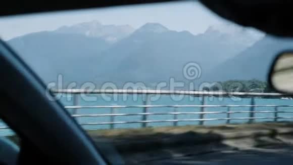 司机开车沿着阿尔卑斯山美妙的蓝色山湖从车内可以看到美丽的阿尔卑斯山视频的预览图