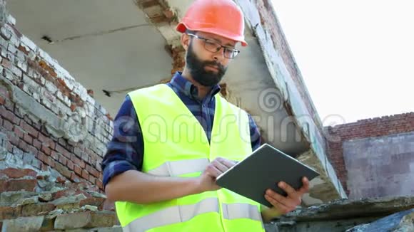 一个工程师在头盔上使用平板电脑建筑拆除计划和查看建筑项目视频的预览图