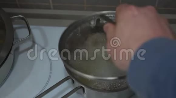 人从炉子上的锅上取下盖子搅动沸腾的汤视频的预览图