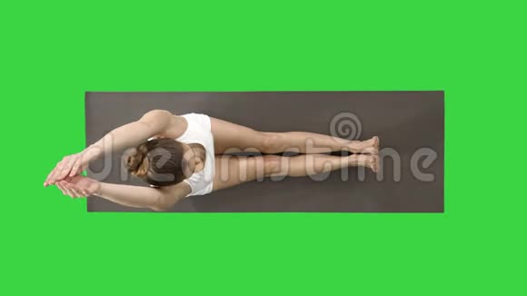 年轻的金发美女正在练习瑜伽做前倾坐式的运动在绿色上摆姿势视频的预览图